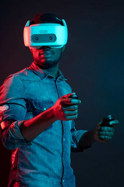 African Man in bianco, indossando VR Headset su sfondo rosso e blu doppio colore . — Foto Stock