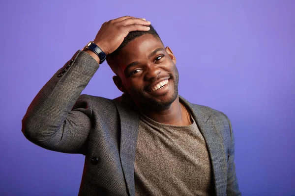 Schöner junger afrikanischer Mann in schicker lässiger Jacke, der über lila Hintergrund lächelt — Stockfoto