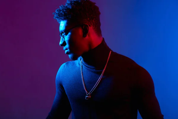 Handsome African man wearing poloneck with amulet on neck against dark wall — Stock Photo, Image