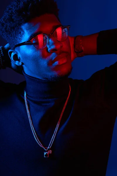 Handsome African man wearing poloneck with amulet on neck against dark wall — Stock Photo, Image