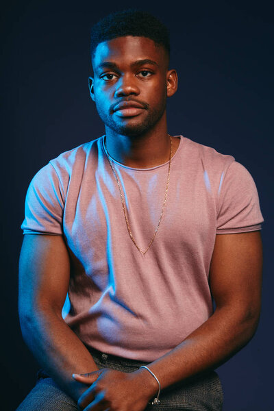 Красивый молодой темнокожий мужчина, одетый в повседневную одежду, позирует на темно-синем
