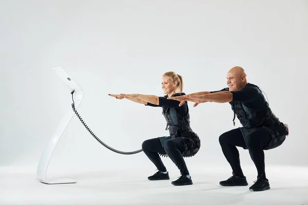 Homme et femme en costumes EMS développant la force de base — Photo