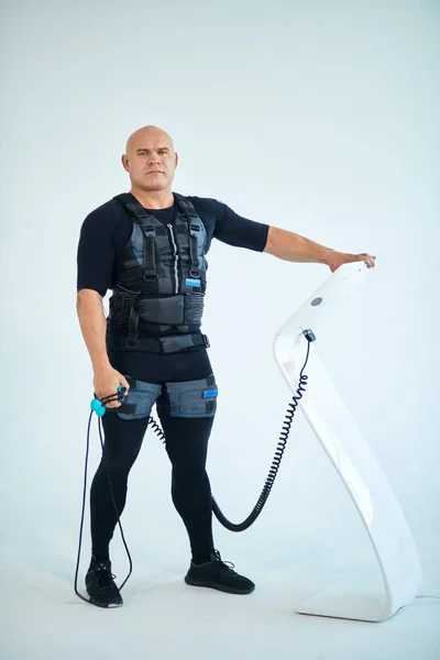 Stark skallig man i EMS kostym hålla Expander och trycka på knappen — Stockfoto