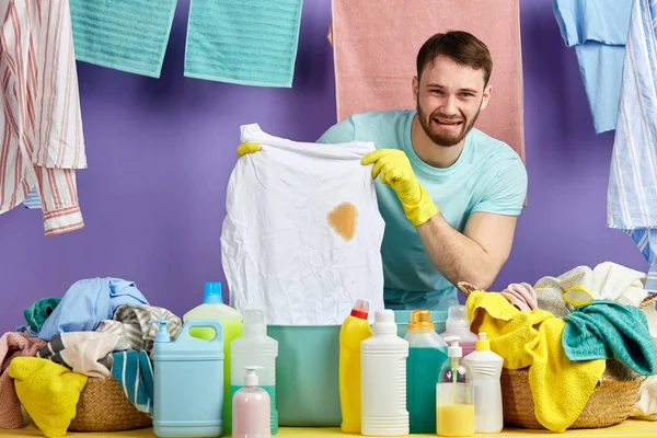 Homme déprimé en gants de protection jaunes montrant son t-shirt sale — Photo