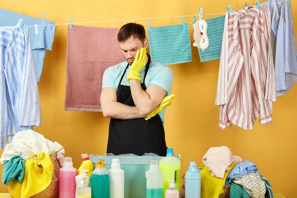 Benadrukte ongelukkige man met de hand op zijn wang met een rust terwijl het doen van huishoudelijk werk, — Stockfoto