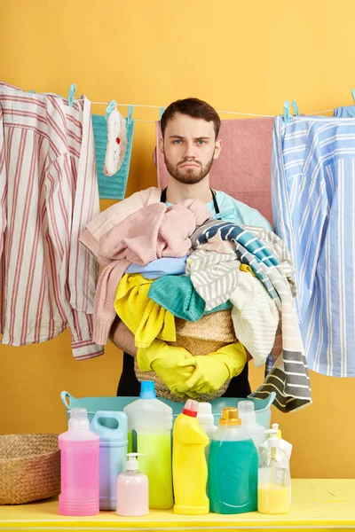 Belle femme de ménage sérieuse avec panier plein de vêtements posant à la caméra — Photo