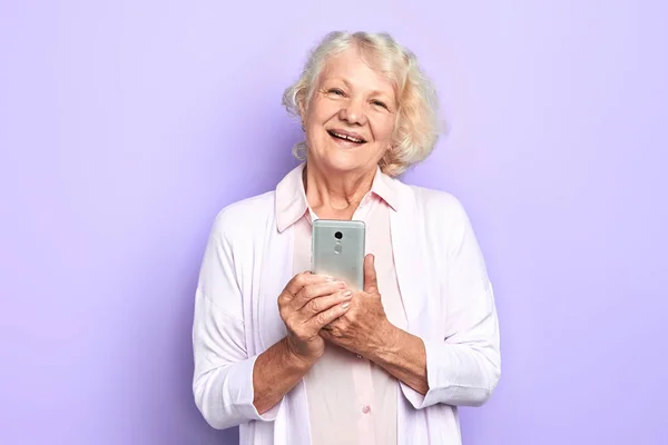 old cheerful happy woman using her smartphone, isolated light blue background