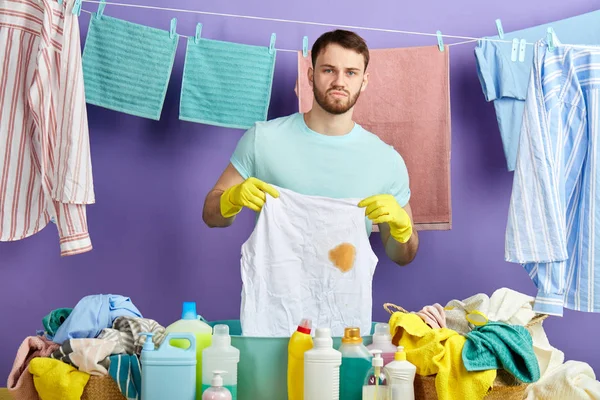 Infeliz haciendo tareas domésticas, sosteniendo ropa sucia —  Fotos de Stock