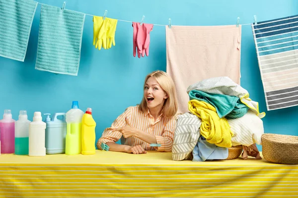 Vidám boldog szőke nő csíkos ing mutatja mosás folyadékot palackokban — Stock Fotó