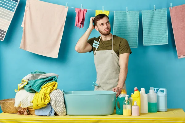 Man kijkt omhoog, scaratching zijn hoofd, verbaasd tijdens het wassen van kleren — Stockfoto