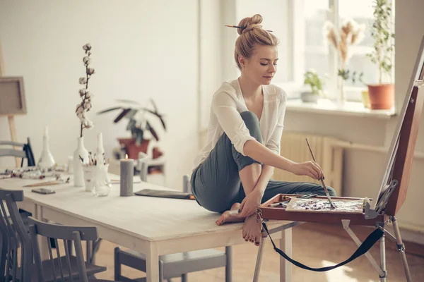 Artista di talento seduto sul tavolo e disegnare il suo quadro a casa — Foto Stock