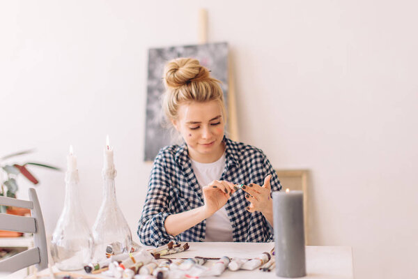 female artist with dirty face sitting at the table in art studio