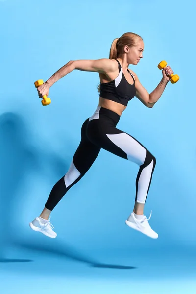 Bastante joven motivado chica fitness corriendo sobre fondo azul — Foto de Stock