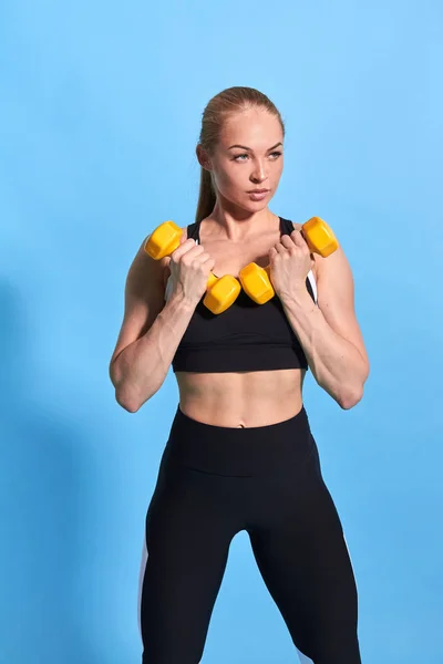 Schöne muskulöse junge Frau in stylischem Sportler beim Heben von Gewichten — Stockfoto