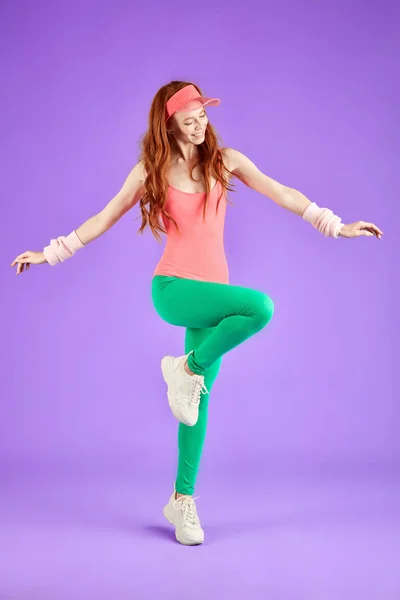 view of young red-haired aerobics girl dressed in 80s style