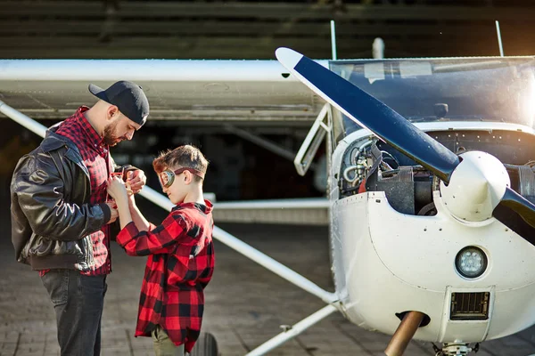 junior and young male aeromodellers stand near single-engine airplane