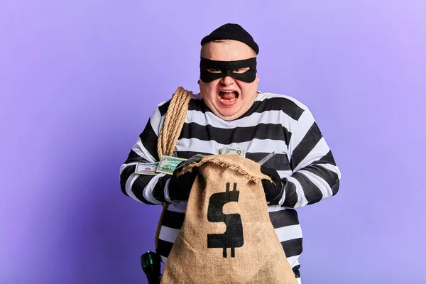 Cruel guilty thief holding a sack and loking at the camera — Stock Photo, Image