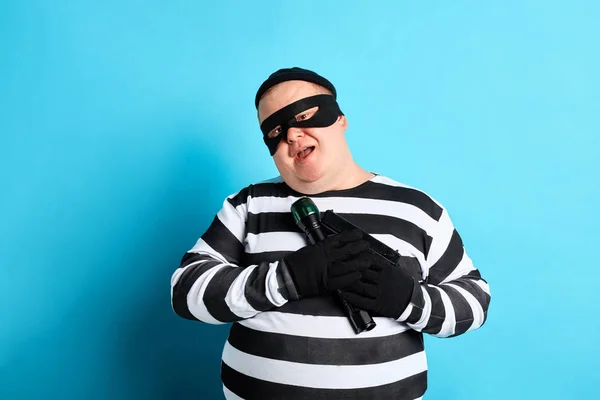 Handsome fat prisoner huggng his gun and tourch and looking at the camera — Stock Photo, Image