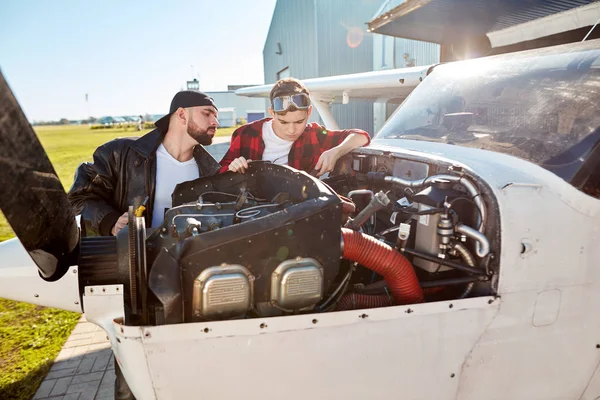 dad and his kid inspecting small propeller plane outside aircraft hangar