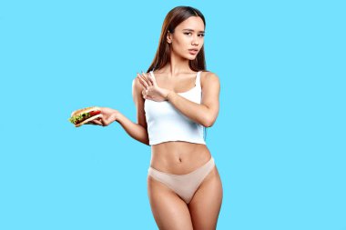 slim sexy girl holding burger, doesnt want to eat it as it has many callories clipart