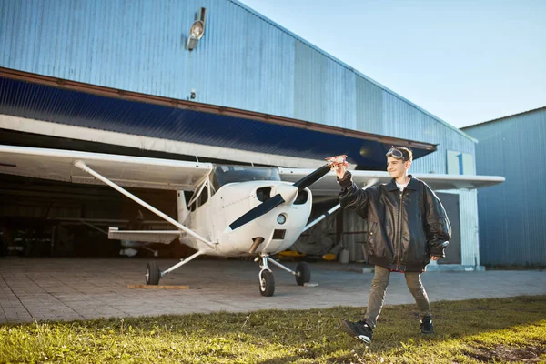 Pequeño niño jugando con pequeño avión de juguete hecho a mano, avión de hélice ligera de pie detrás — Foto de Stock