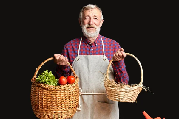 Amistoso granjero macho con barba, presentando cestas con verduras y huevos — Foto de Stock