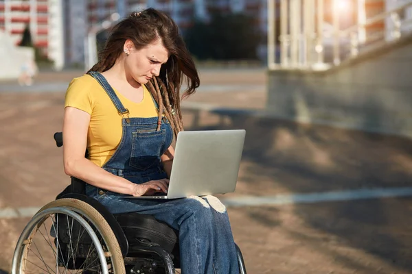 Stilvolles behindertes Mädchen in lässiger Kleidung, das sich auf die Arbeit mit Laptop konzentriert — Stockfoto