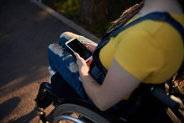Девушка-инвалид читает сообщения по мобильному телефону — стоковое фото