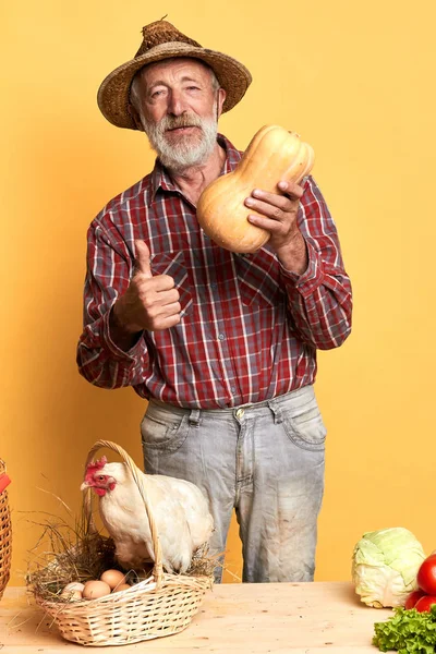 Mature village man with pumpkin in his hand, showing thumbs up