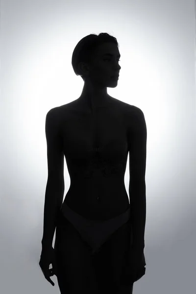 Zwart-wit silhouet van jonge, sportieve meisje in stijlvolle witte lingerie — Stockfoto