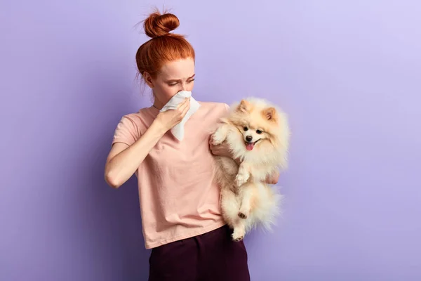 Mulher segurando um cão que está fedendo — Fotografia de Stock