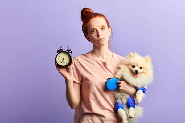 Güzel genç uykulu mutsuz kadın elinde bir saat ve köpeği tutan — Stok fotoğraf