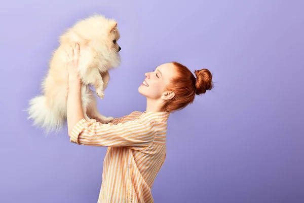 Donna dai capelli rossi che tiene un bel cane di razza soffice sopra la testa — Foto Stock