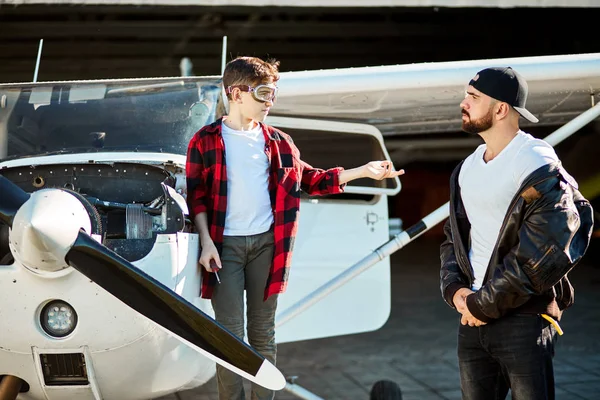 Adolescente menino com chave de fenda, pedindo ajuda pai, de pé perto de avião leve — Fotografia de Stock