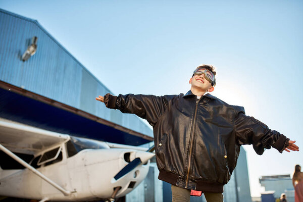 happy kid in aviator glasses playing in front of white light private plane