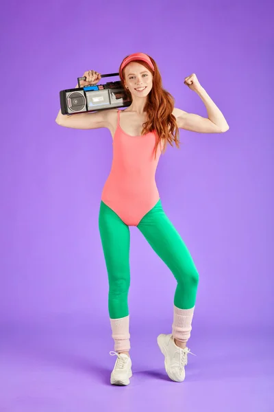 sporty girl standing with portable audio player and showing biceps