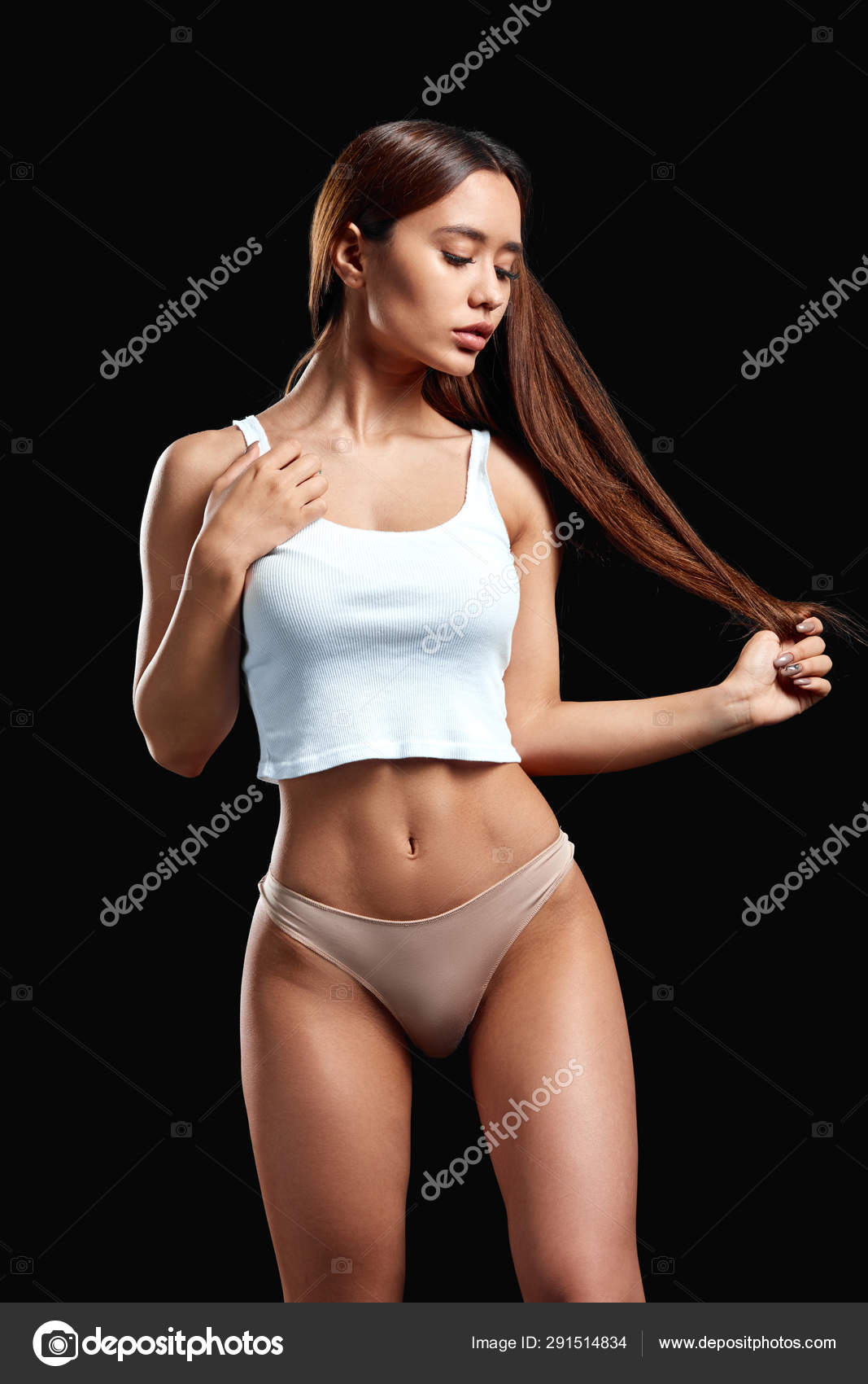 Slim well-built girl in stylish underwear looking down, touching