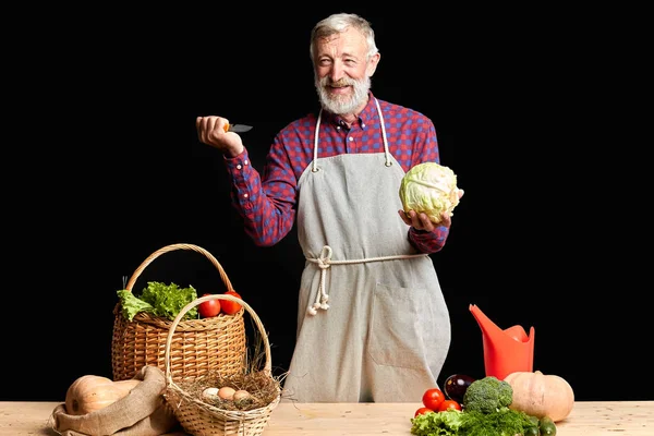 Bonito homem maduro na limpeza avental e corte de vegetais orgânicos — Fotografia de Stock
