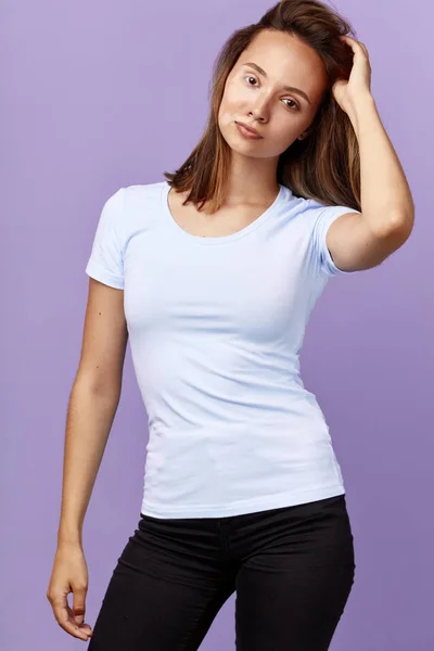 Menina atraente em t-shirt branca e jeans com braço levantado posando para a câmera — Fotografia de Stock