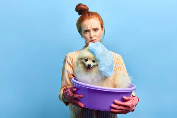 sad red-haired girl holding absin with dog wearing swimming cap