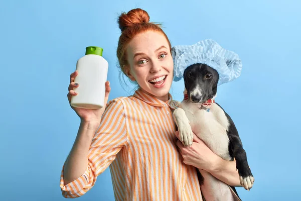 Excitada chica divertida sosteniendo un champú y su adorable perro — Foto de Stock