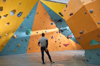 Fiziksel engelli Boulderer renkli yapay duvarlara düşünceli bakıyor