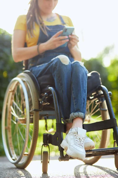 Junge attraktive Frau im Rollstuhl textet mit ihrem Handy — Stockfoto