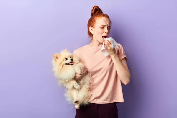 Menina engraçada segurando um cão fofo e espirrando — Fotografia de Stock