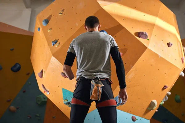 Low angle back view of physically impaired sportsman staring at climbing wall — Stock Photo, Image