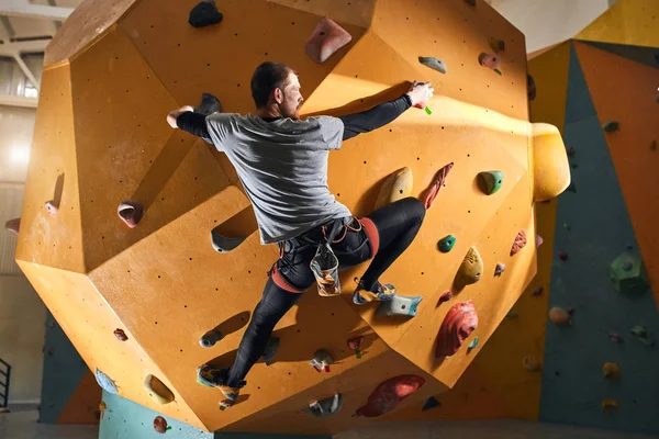 Escalador con problemas físicos tratando de llegar a la cima de la pared de escalada artificial —  Fotos de Stock