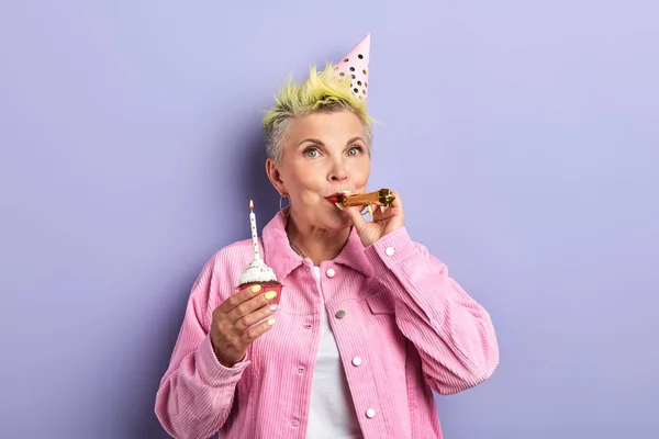 Senior woman using party whistle — стоковое фото