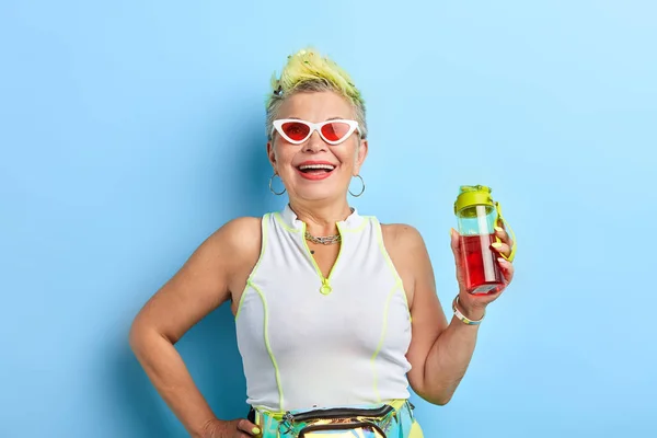 Positive Modeunternehmerin mit einer Hand auf der Hüfte, die eine Flasche Saft hält — Stockfoto