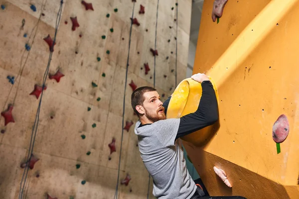 Strong rock-climber with physical disability overhanging at big hold