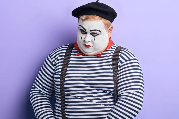 Portret smutny nieszczęśliwy clown depresji patrząc w dół na niebieskim tle — Zdjęcie stockowe